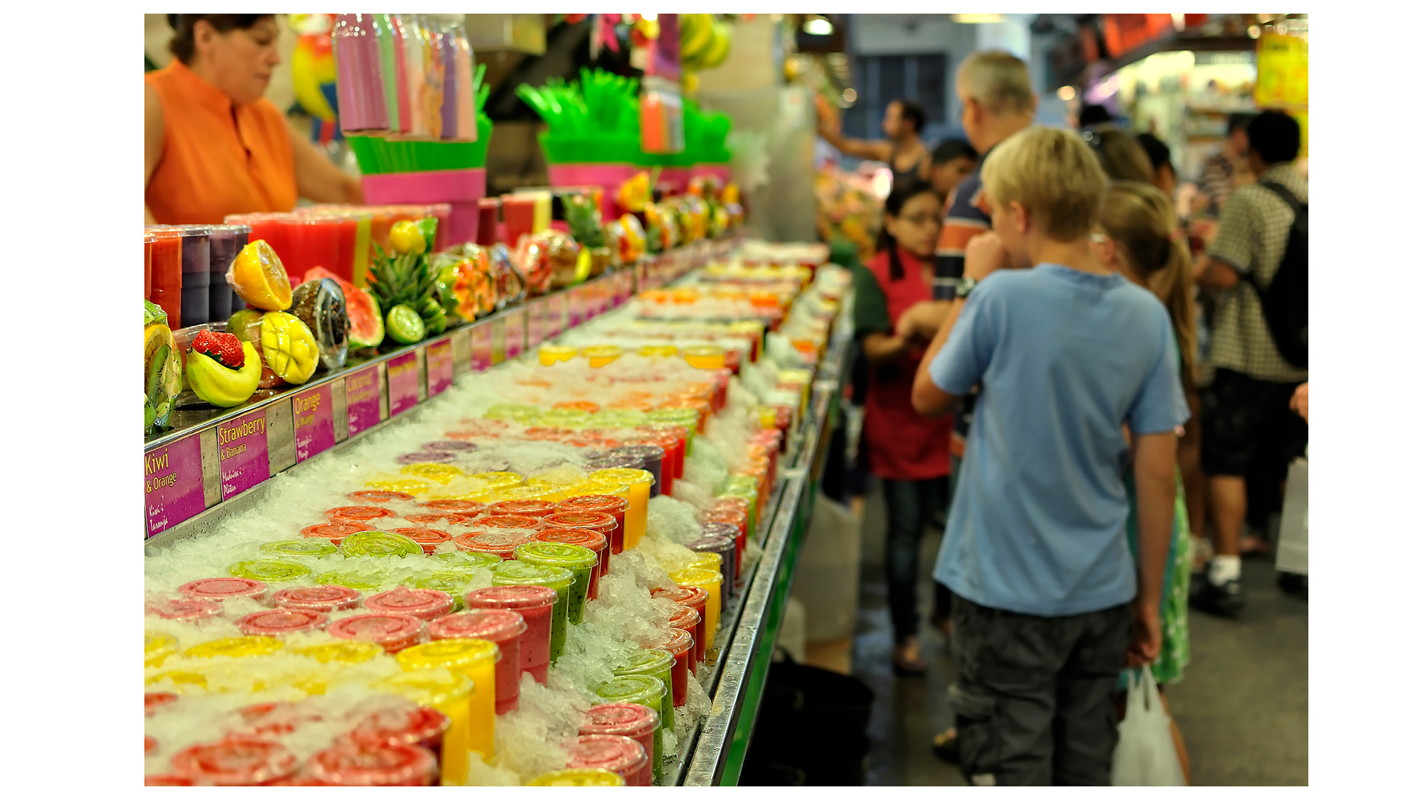 Child browses fruit rows of fruit juices in Barcelona’s historic La Boqueria market