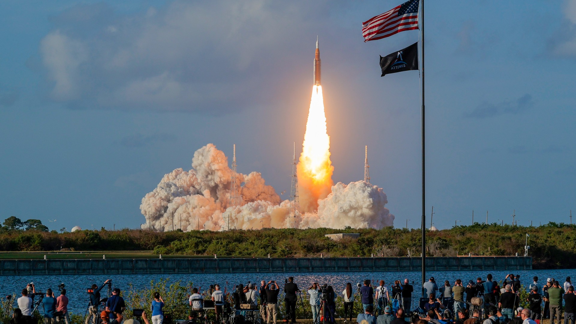 يُطلق صاروخ فوق عمود من النار في الخلفية، خلف حشد من الناس