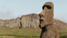 A moai statue in front of a rocky hill on Easter Island