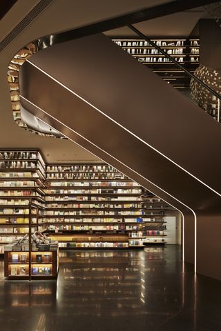 A view underneath the escalators towards the illuminated bookshelves beyond