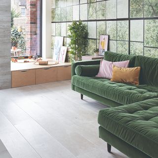 A living room with a photographic wall mural and a corner green velvet sofa with two contrasting cushions in one corner