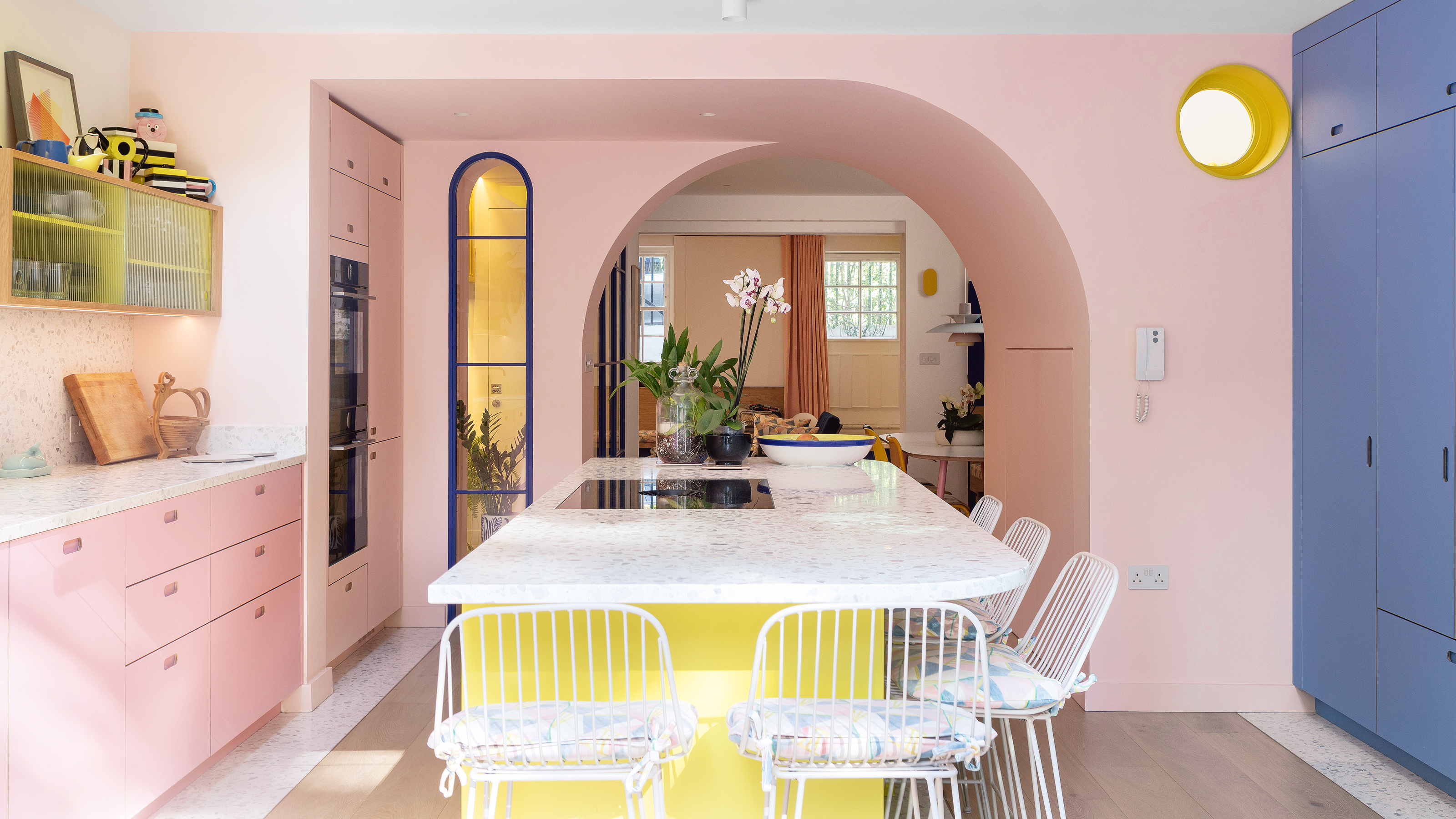 kitchen with pink and blue cabinets, a yellow island and pink walls