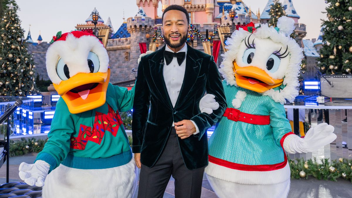 Donald and Daisy Duck pose with a sharp-suited John Legend in the magical surrounds of Disneyland.