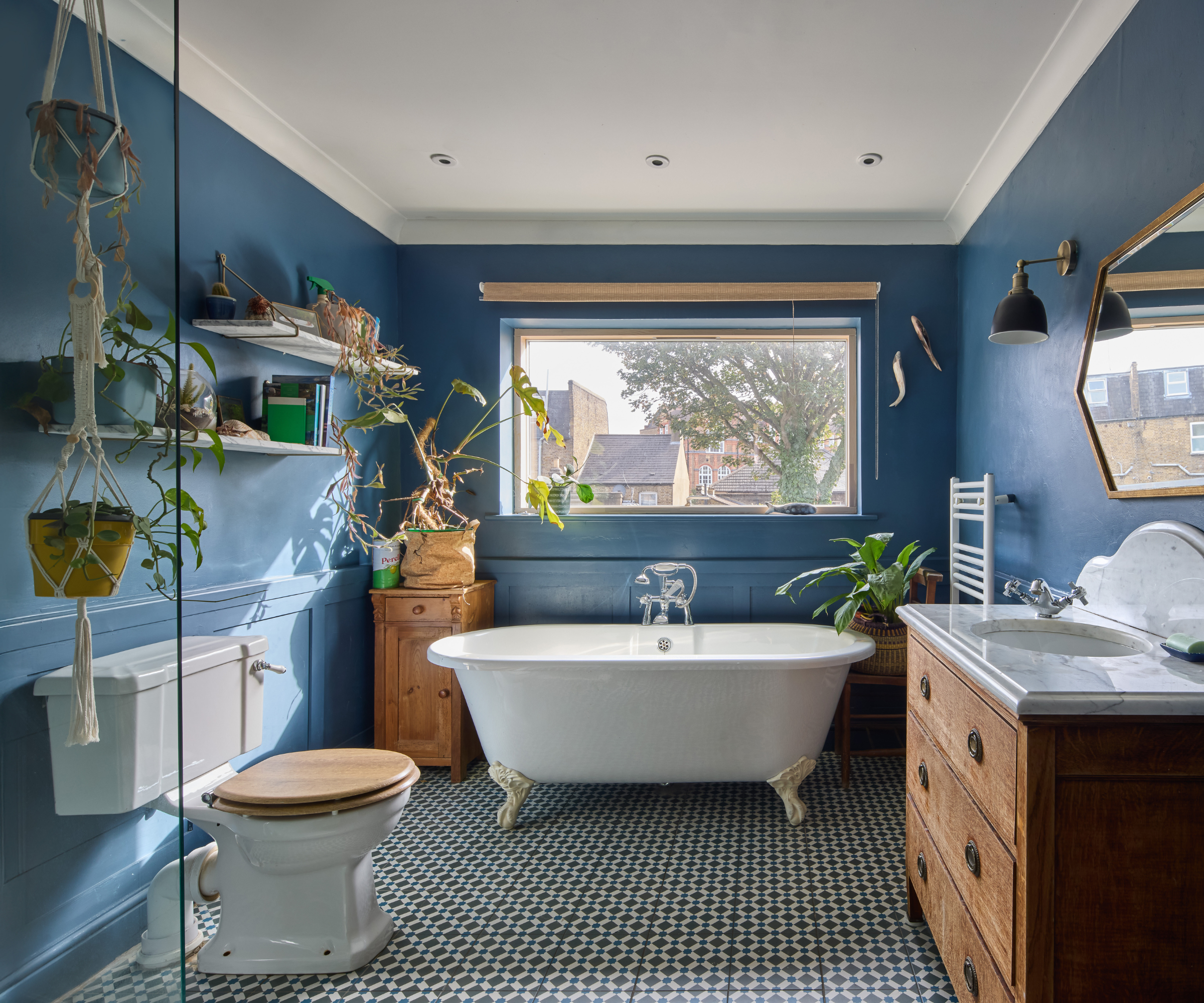 Bathroom with blue walls and freestanding bath next to a window