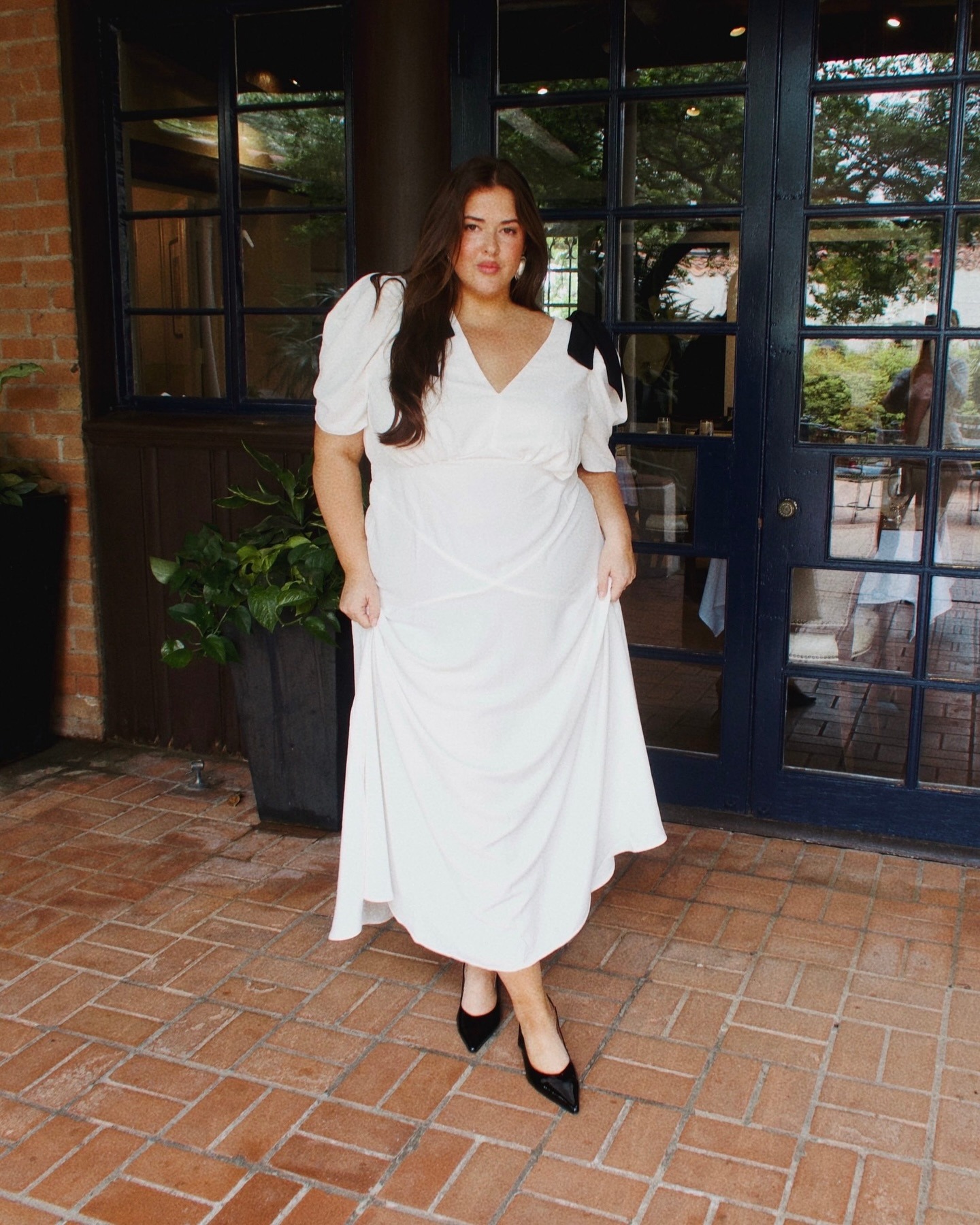 Plus size bride wearing white maxi dress with black bows.