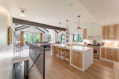 A modern open plan kitchen with wooden floors and white countertops