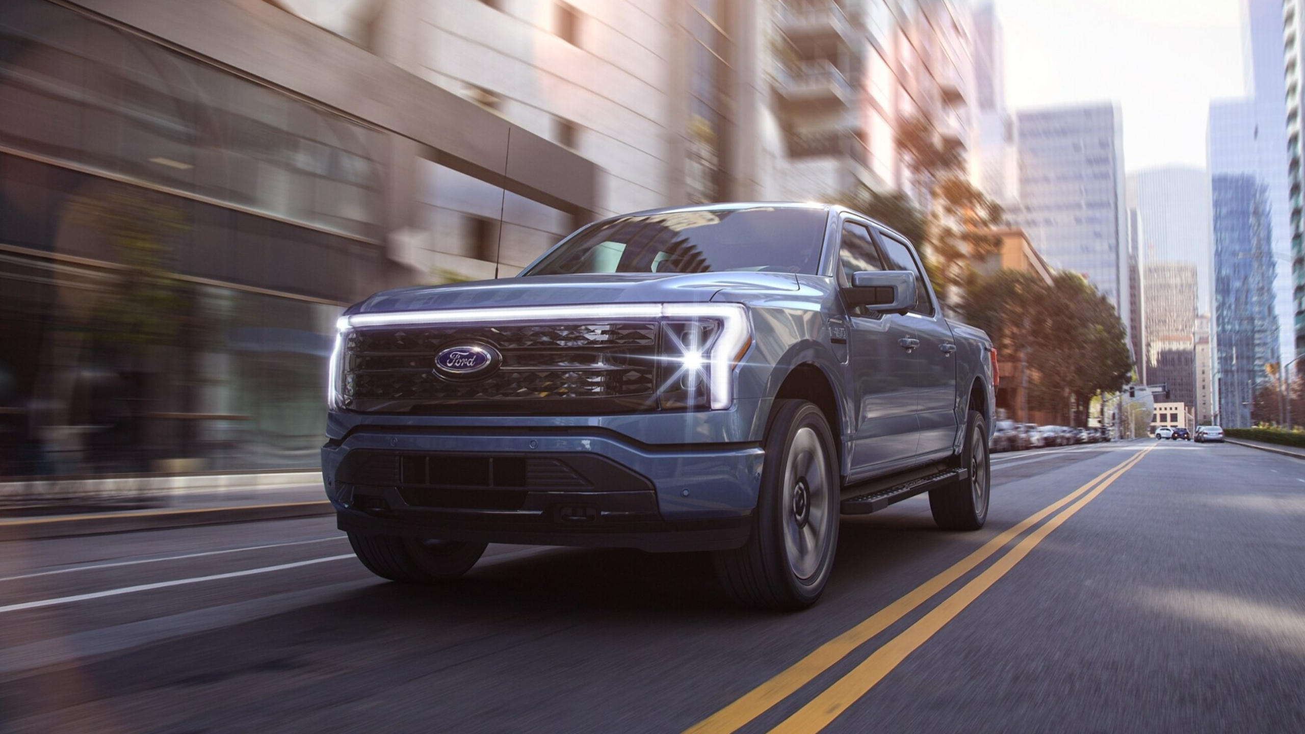 Ford F-150 Lightning beim Fahren auf einer Straße, im Hintergrund sind Hochhäuser zu sehen