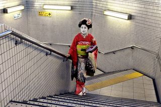 ’Geisha in Subway Station’, Kyoto, Japan, by Steve McCurry, 2007. A Geisha walking up a white tiled staircase.