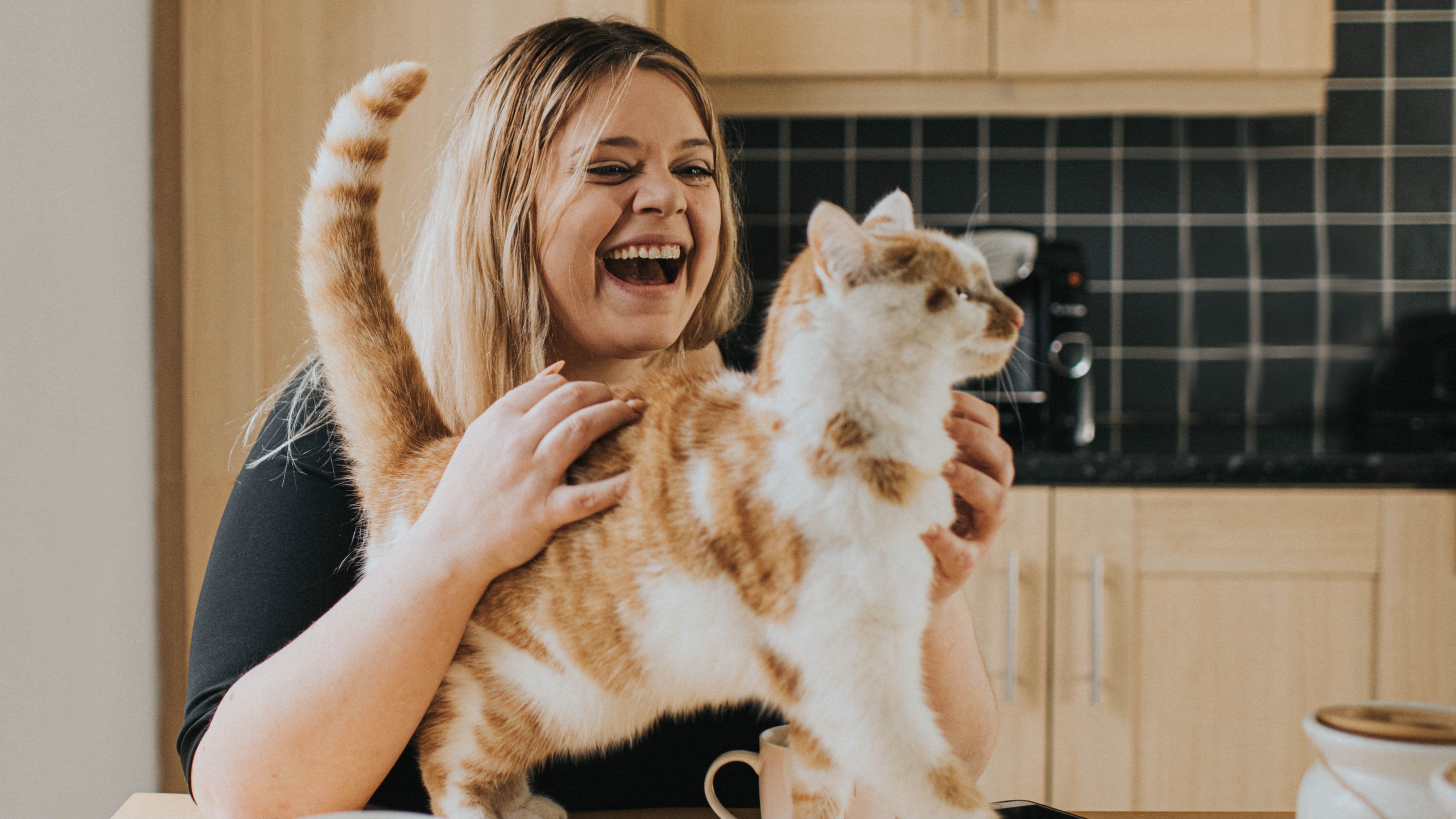 Woman laughing while she strokes cat