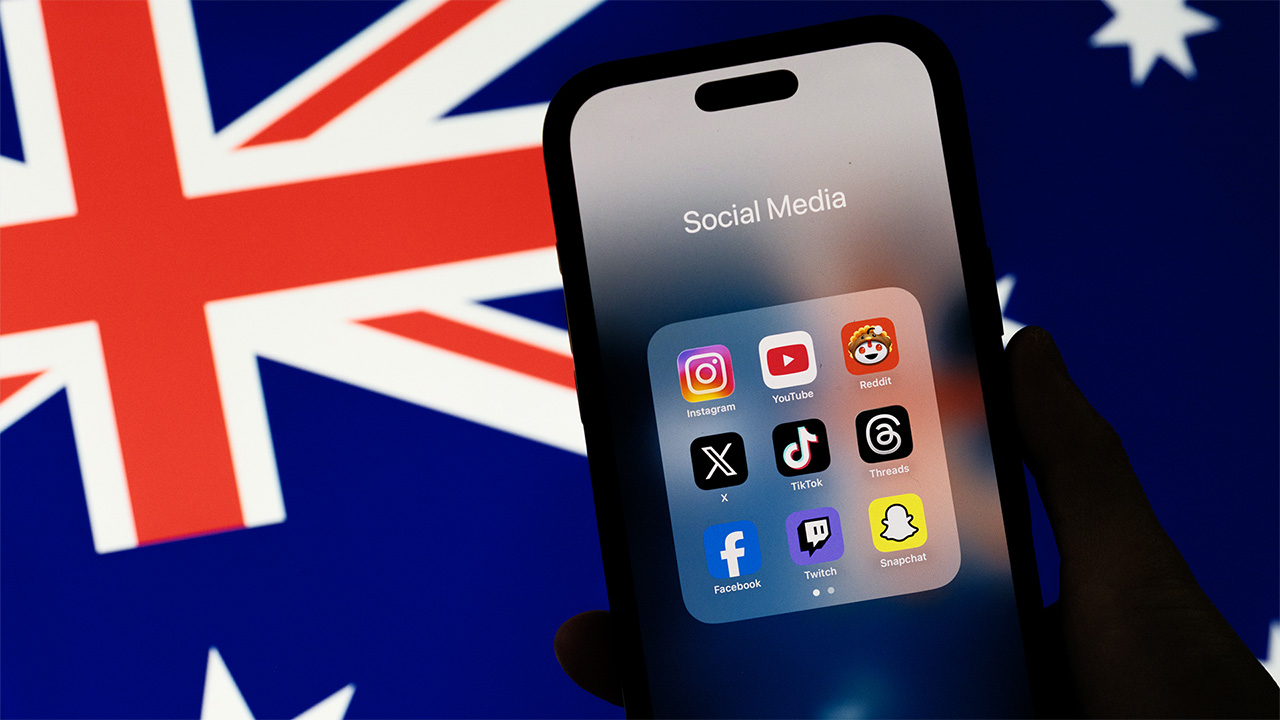 Person holding phone with social media apps displayed in front of an Australian flag