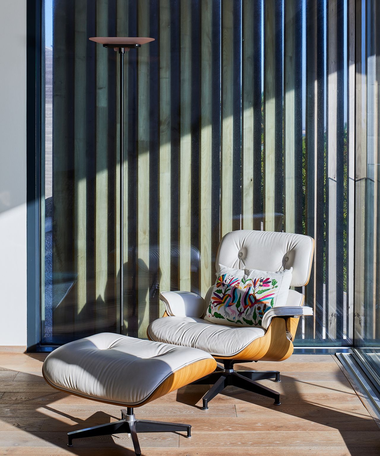 a swivel armchair in mid-century modern style in front of floor to ceiling glazing