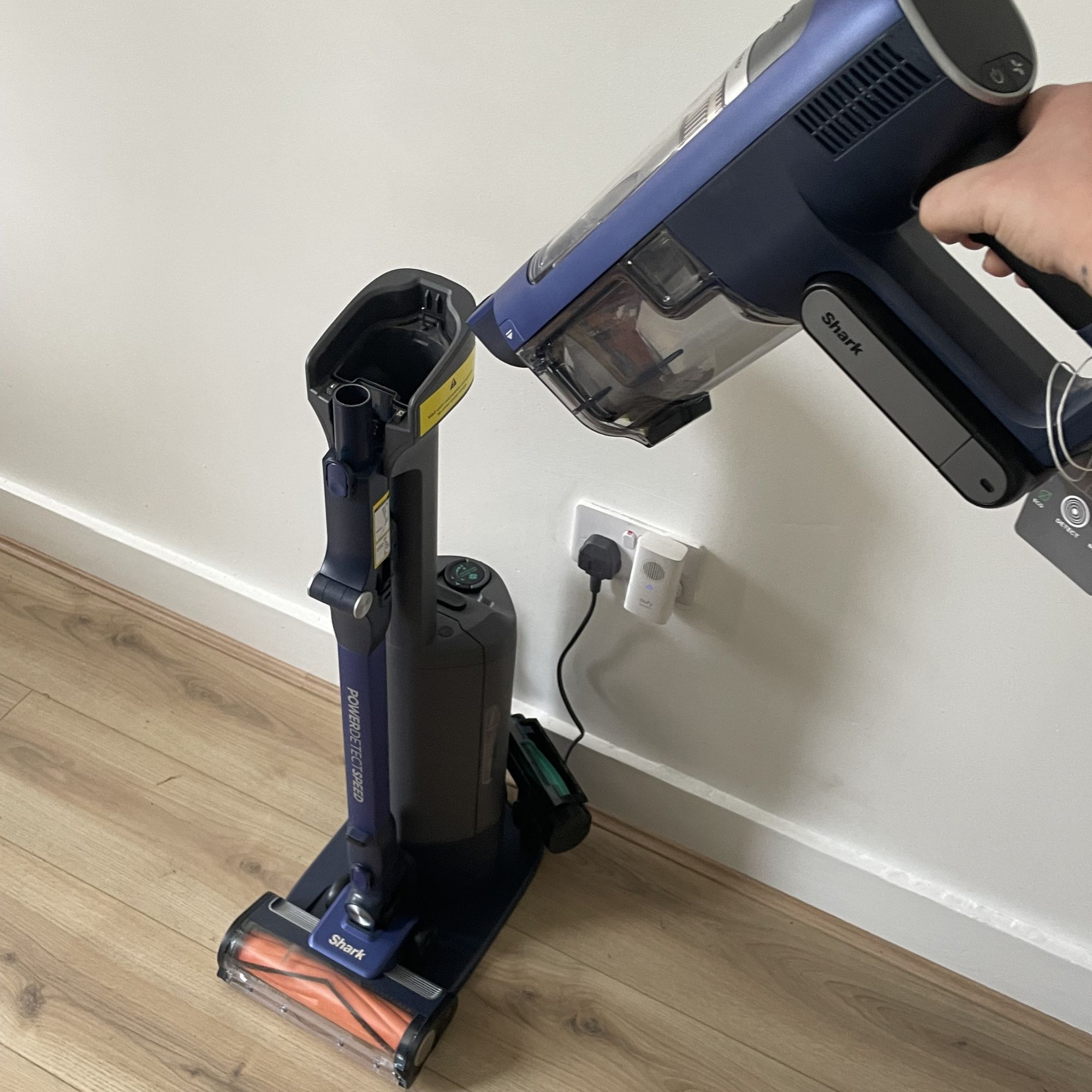 Shark PowerDetect Speed Clean and Empty Pet Pro sitting on wood-effect flooring in front of a white wall