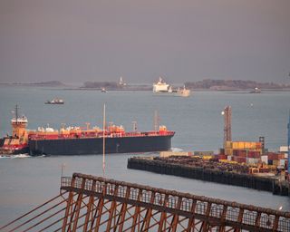 Container ship with cranes at a harbor with Nixes Mate and Boston Lighthouse in the background, Boston Harbor