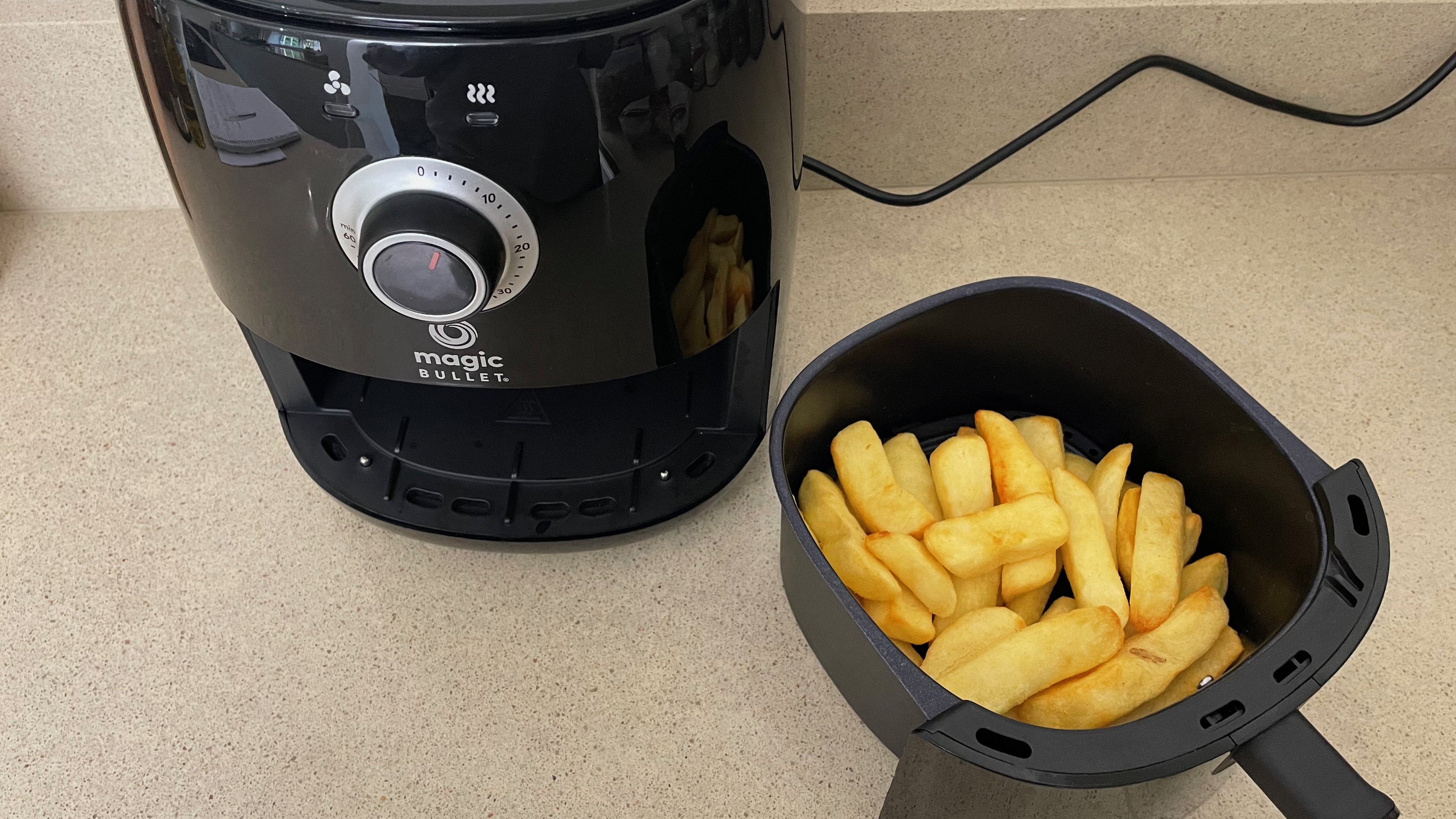 Magic Bullet Air Fryer next to tray of uncooked chips