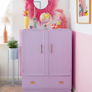 corner of room with purple painted cabinet and pink mirror above