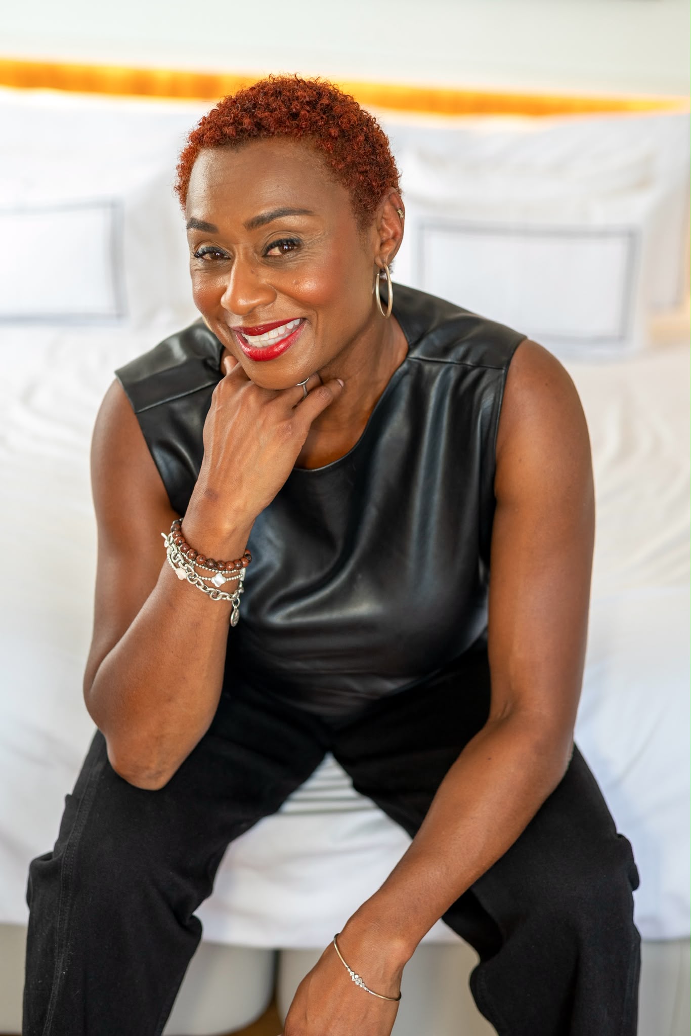 A woman sitting with one elbow on her knee, looking to camera and wearing all black