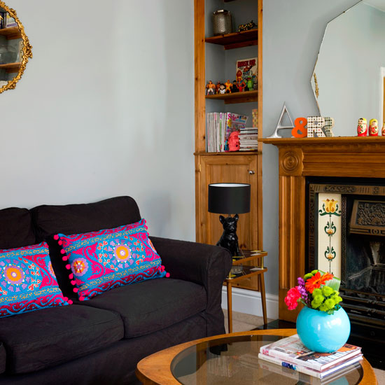 living room corner with dark grey sofa built wooden units fireplace and coffee table