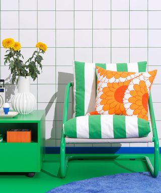 A green metal chair with green and white striped cushions in front of a black and white checkered wall