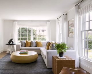A family room with white walls, grey sofa and yellow scatter cushions