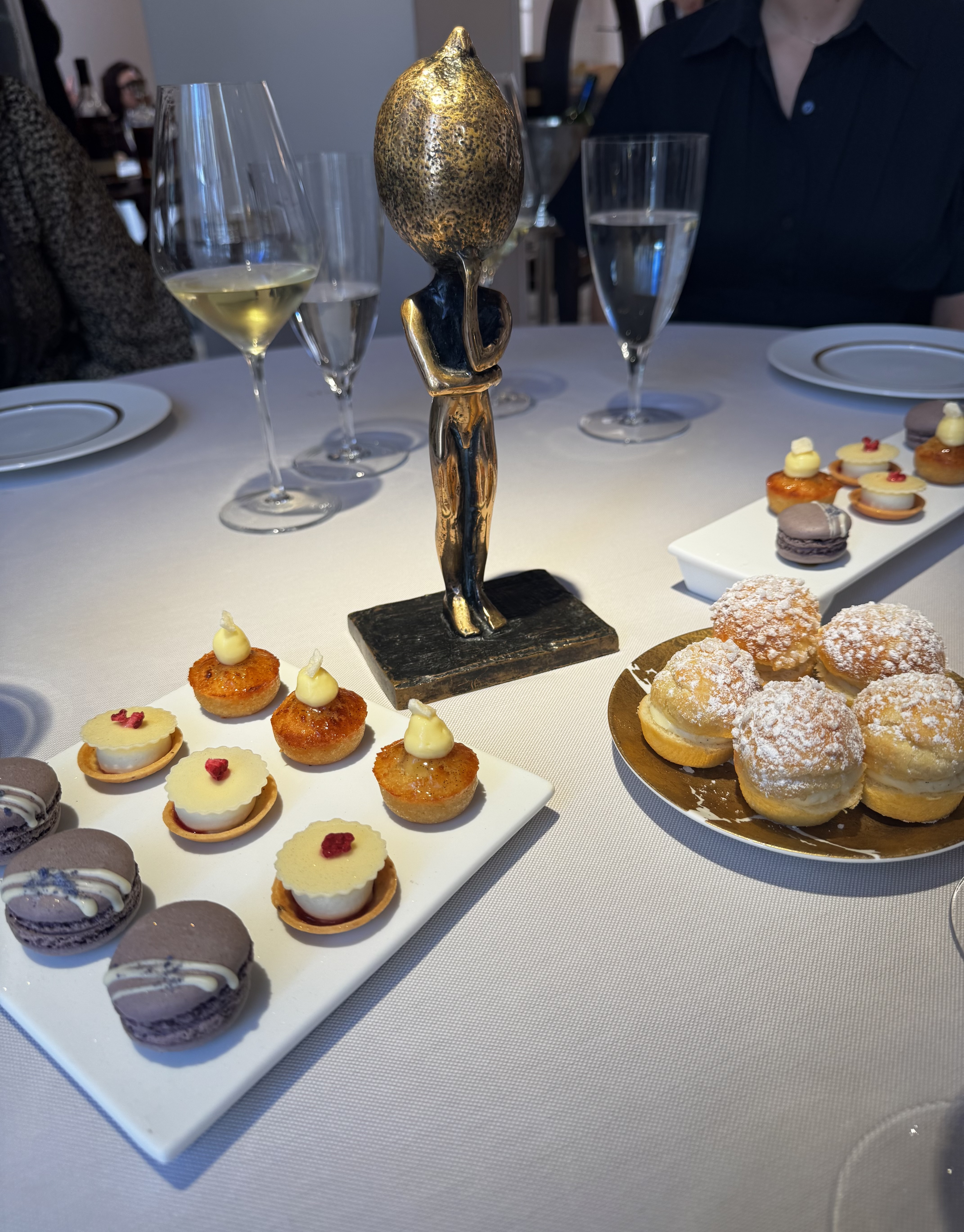 A table with desserts and a statue of a person with a lemon for a head