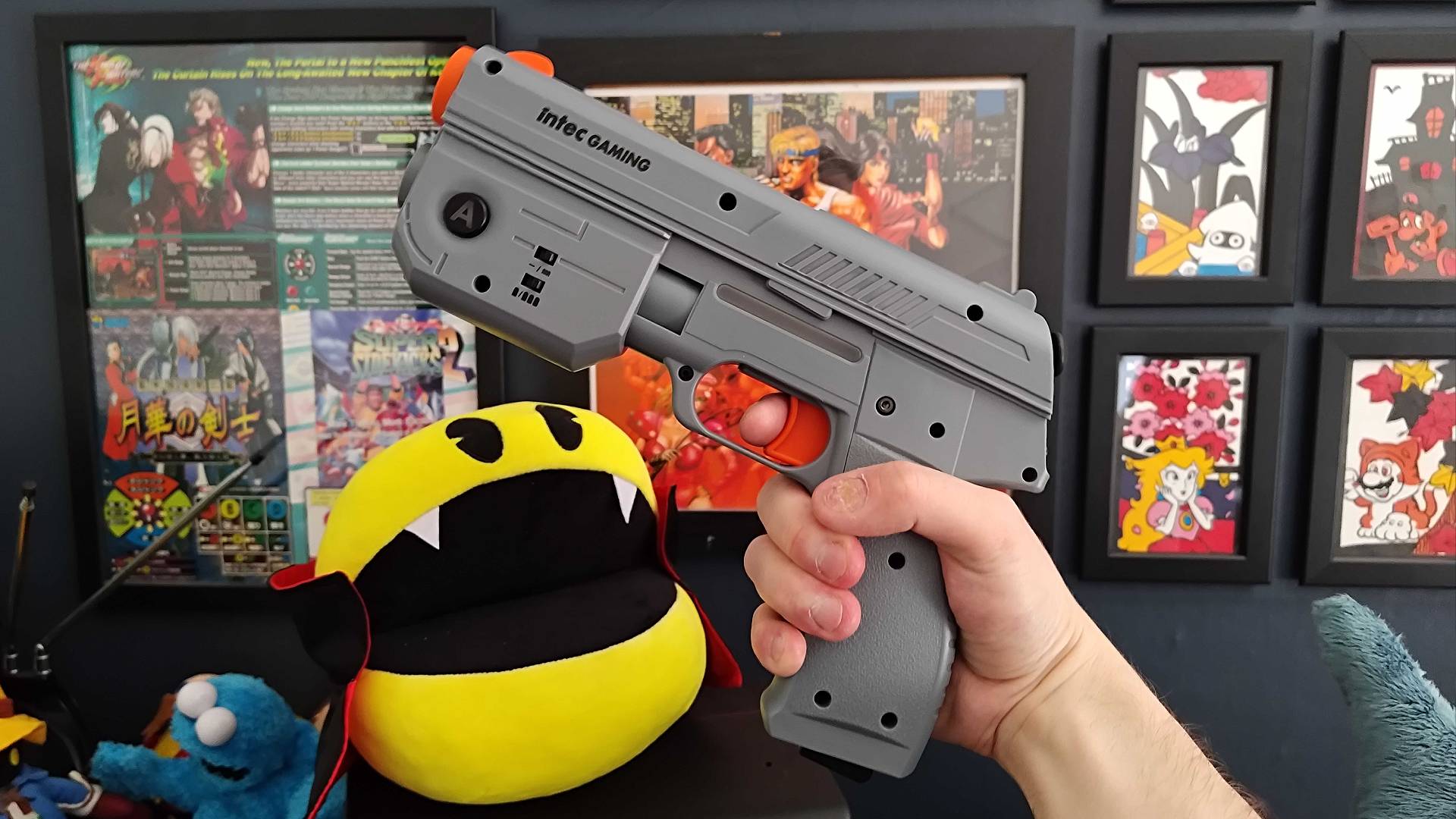 Intec Gaming PS2 light gun in gray next to vampire Pac-Man plush.
