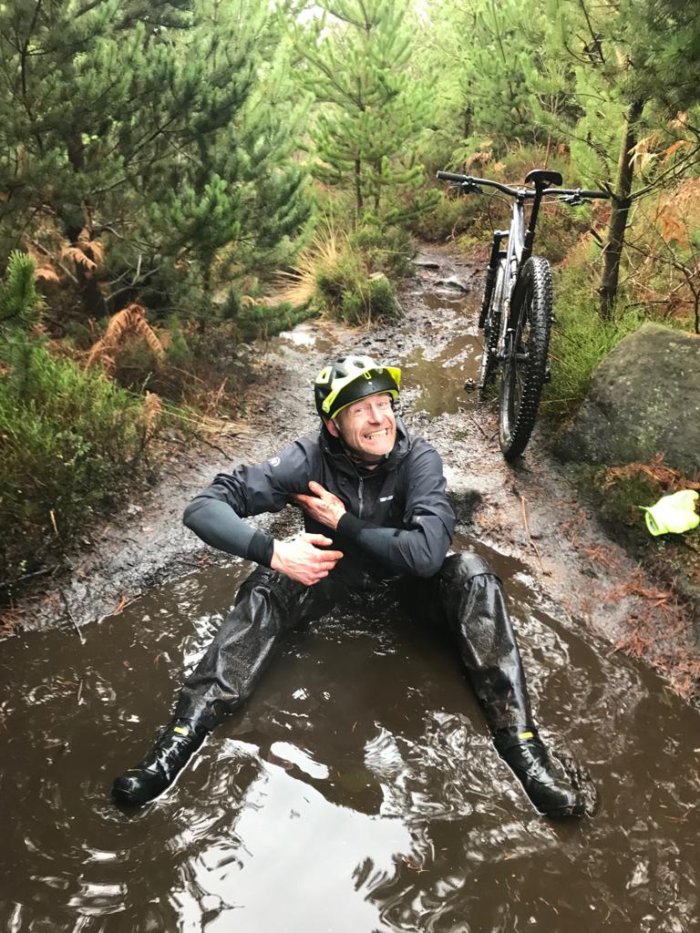 A man washing himself in a muddy puddle