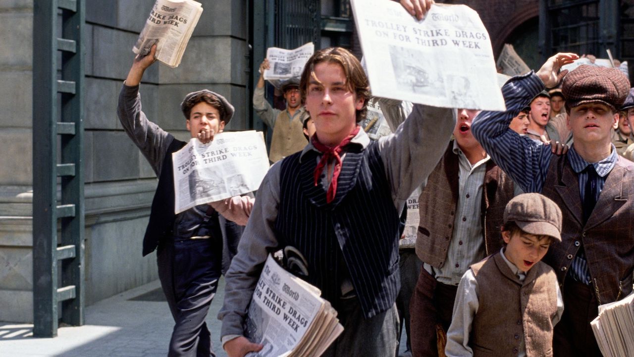 Christian Bale holding up newspaper in Newsies