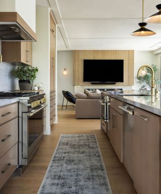 A wooden kitchen with a patterned runner rug and mixed metal hardware