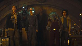 Fern, SM-33, K.B, Jod, Neel, and Wim staring at something in a big room in Star Wars: Skeleton Crew