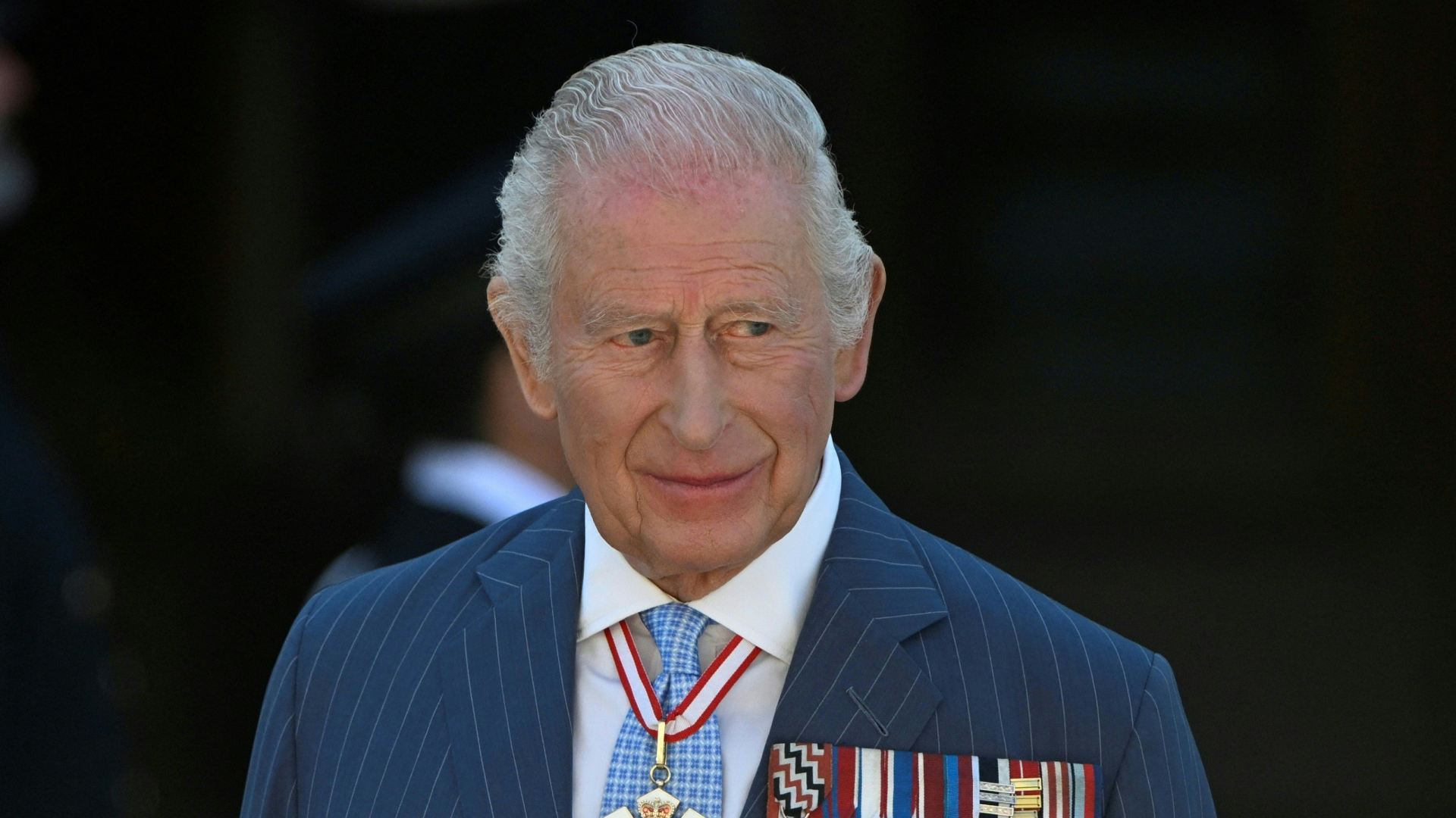 King Charles wearing a blue striped suit with medals