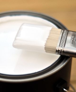 paint brush resting on an opened tin of white paint
