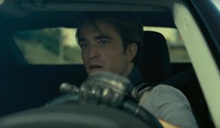 Tenet Robert Pattinson driving with a concerned expression