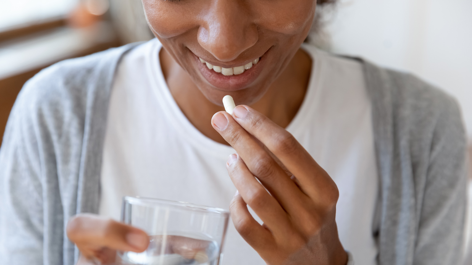 woman taking a supplement with water
