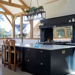 dark blue kitchen with beams and industrial lighting above island