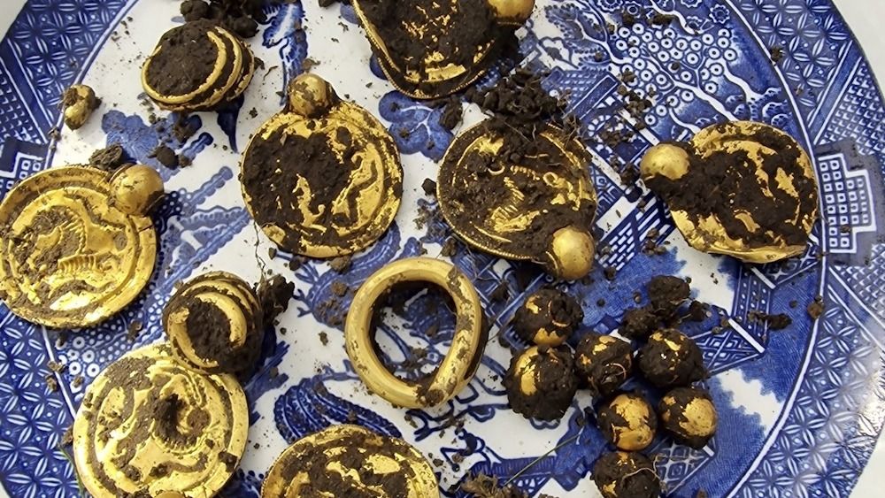 A collection of gold jewelry caked in dirt. 