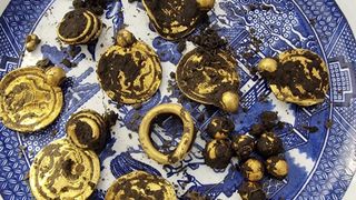 A collection of gold jewelry caked in dirt.