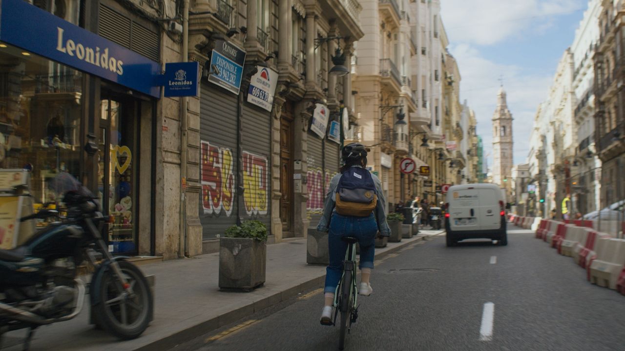 A cyclist is shown riding down a busy city street