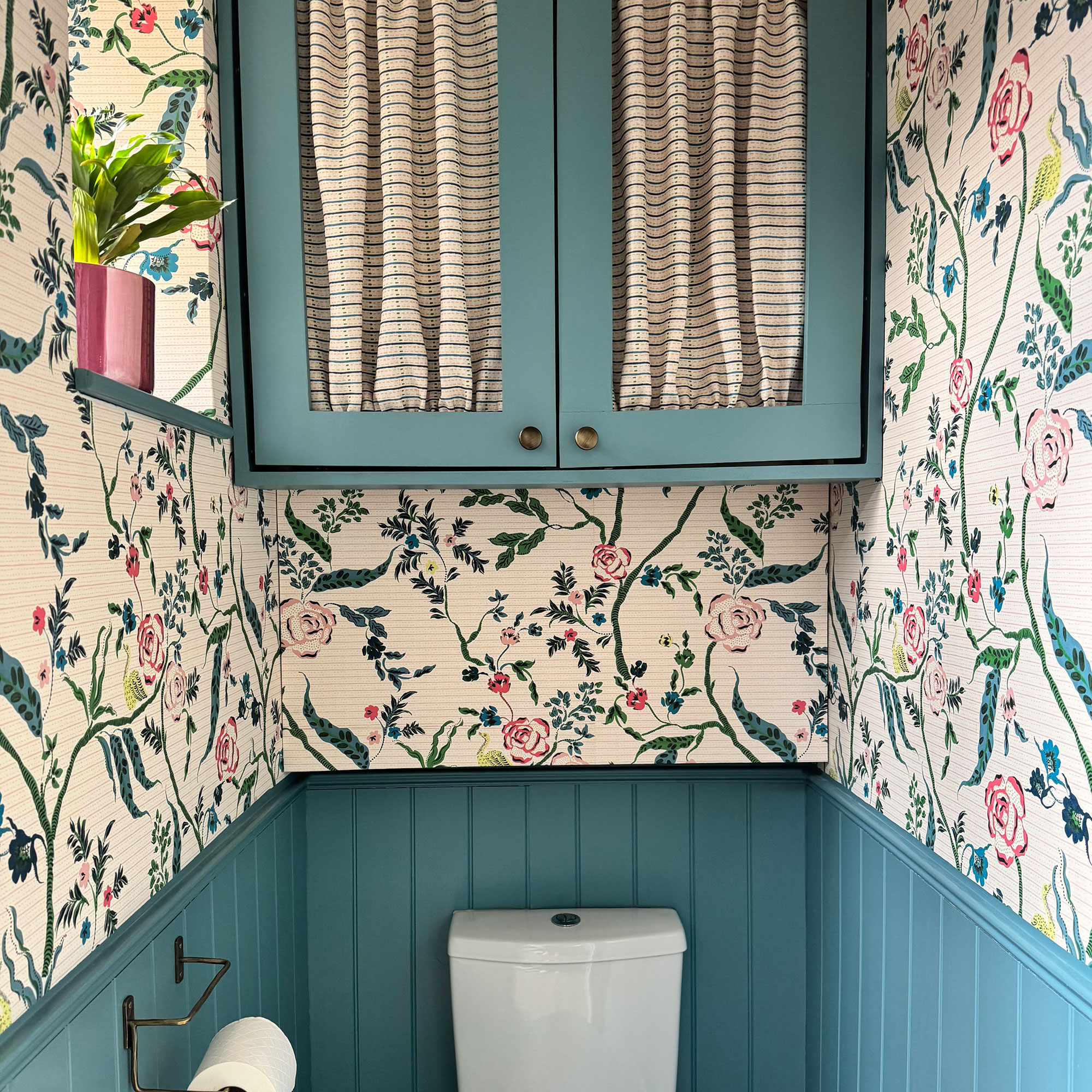 Small bathroom with blue half wall panelling and colourful patterned wallpaper above