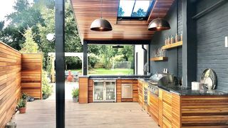 An outdoor kitchen with smart appliances and a garden in the background