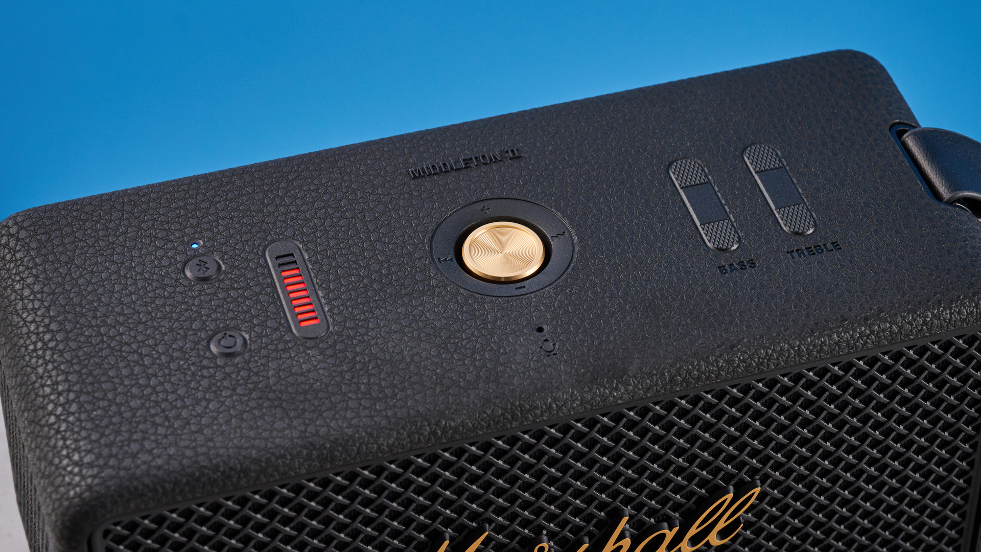 The Marshall Middleton II Bluetooth speaker in Black and Brass, with a blue wall in the background