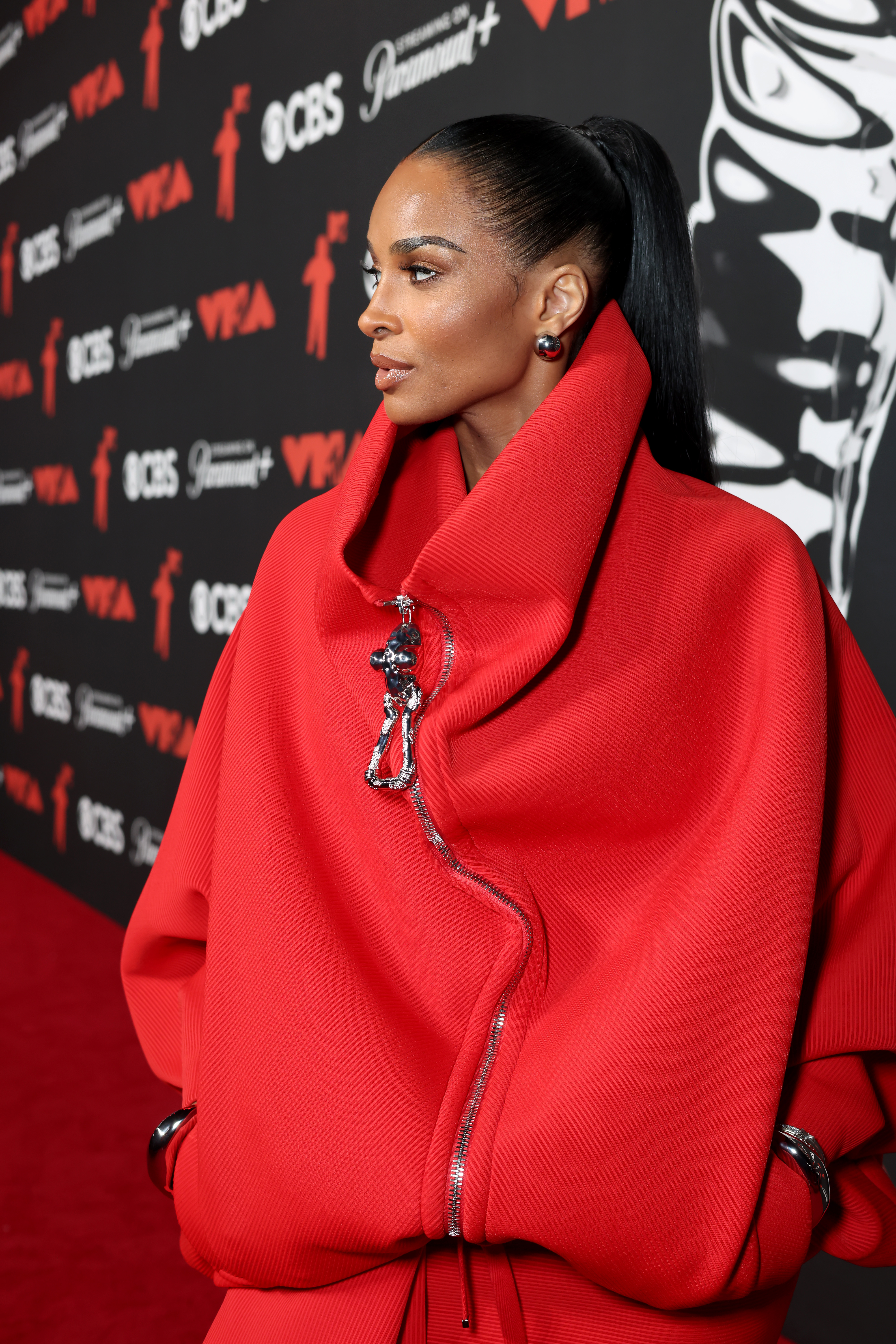 ciara posing on the red carpet in a red sweater dress
