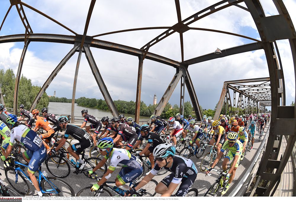 The peloton crosses a bridge in the Italian countryside.
