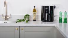 Dreo air fryer in modern grey kitchen with bottle of Odysea extra virgin olive oil with artificial houseplant near sink
