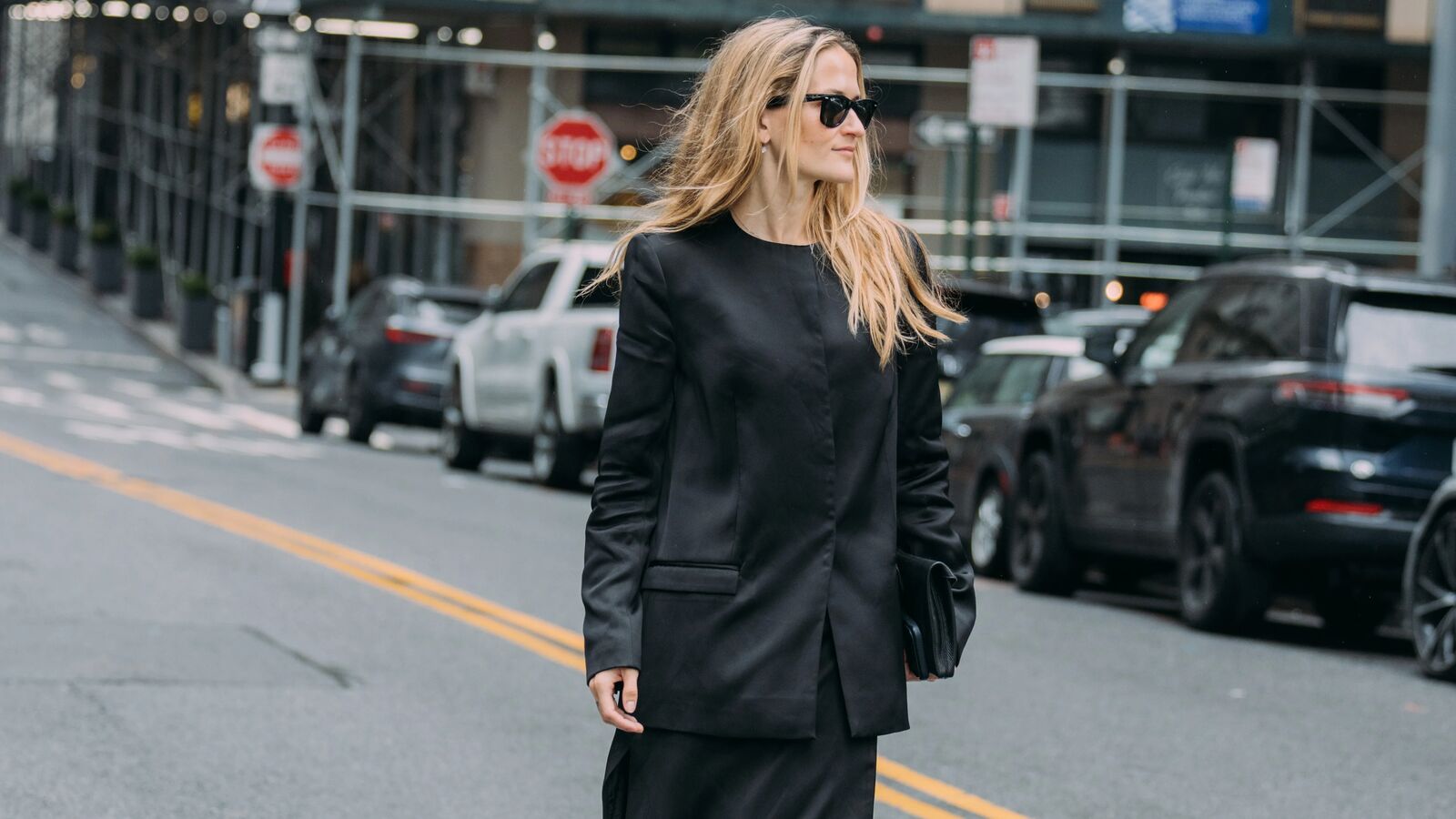 Woman wearing a collarless black satin blazer. 