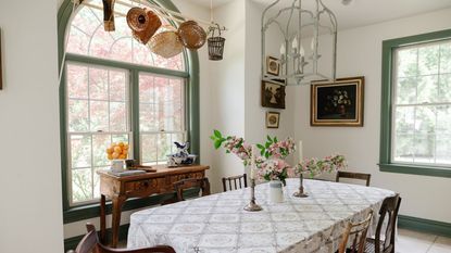 Vintage dining room with arched window, long dining table with white tablecloth, wood chairs and pendant light