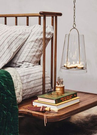 A bedside table with books and a unique bedside lamp