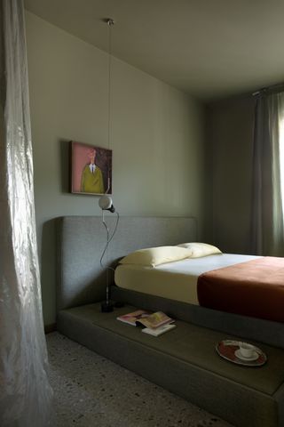 A bedroom with dark green walls, a gray headboard, and orange bed sheets