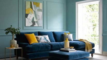 Blue living room with wall panelling and blue velvet sofa