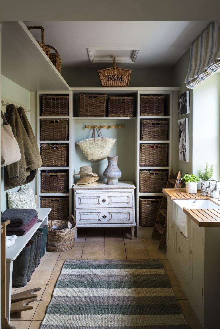 An example of mudroom ideas showing a small mudroom with wicker basket storage, coat pegs and a sink area