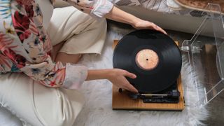 woman putting on a vinyl record on a turntable